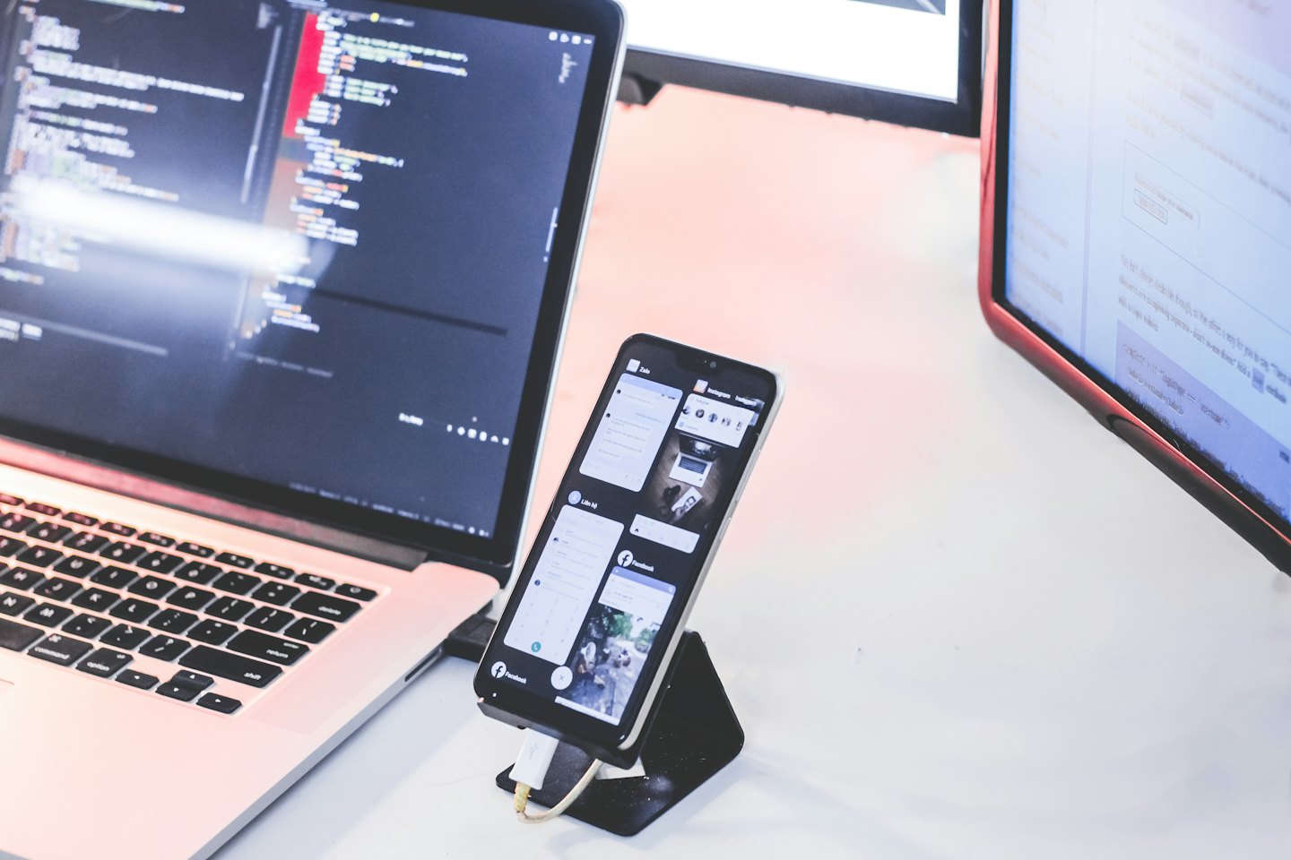 Laptop and monitor displaying code on a white desk.
