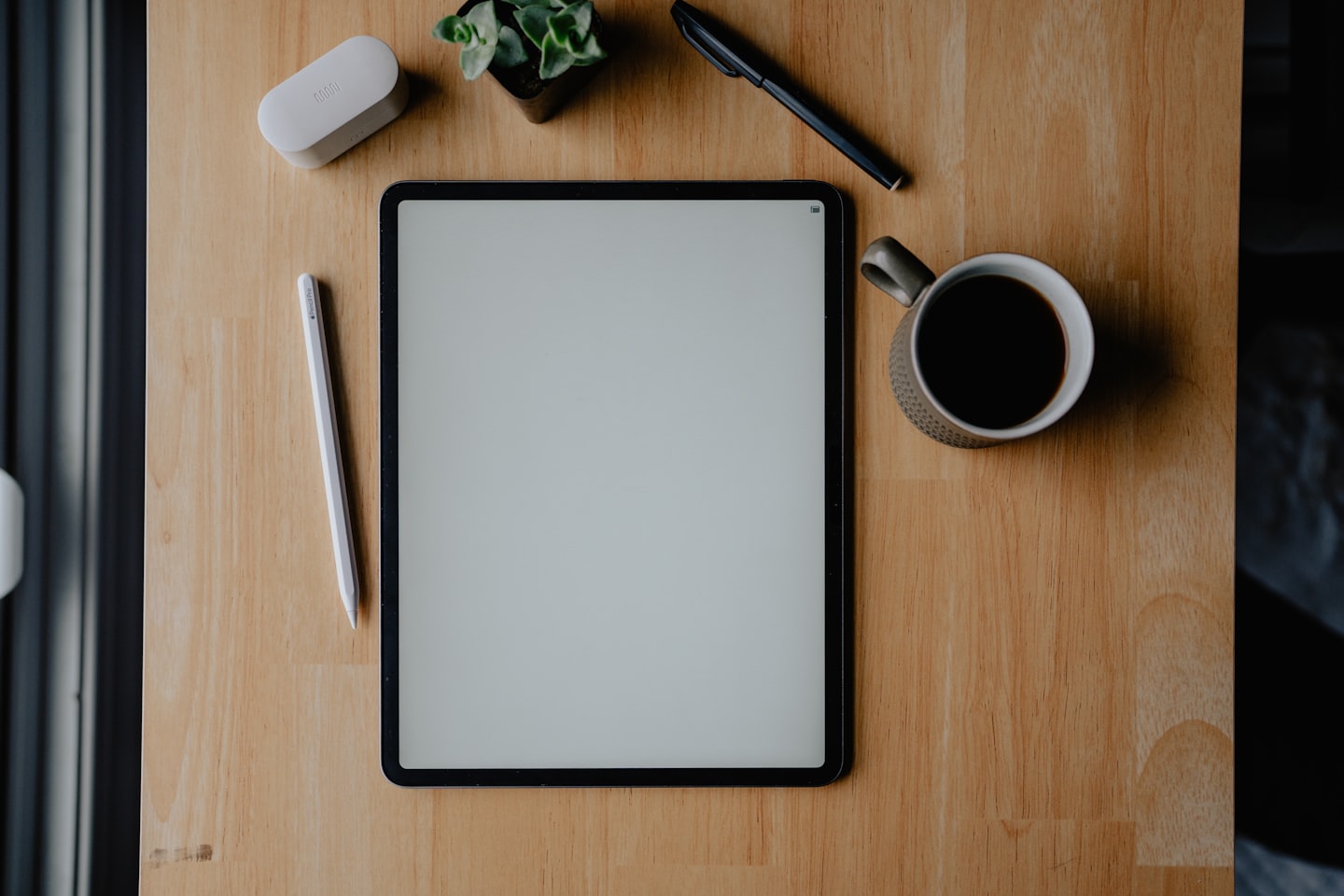 Tablet and office supplies on a wooden desk.